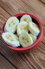 Fresh ripe organic sliced bananas in a ceramic bowl on wooden