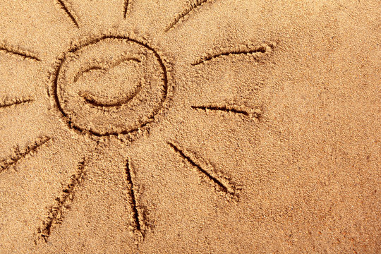 Smiling Sun happy smiley face drawn in sand on a summer beach photo