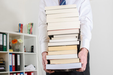Man carrying a pile of books - obrazy, fototapety, plakaty