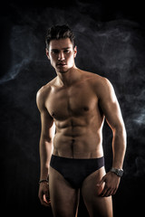 Fototapeta na wymiar Handsome, fit young man wearing only underwear standing on black