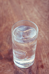 Drinking water with ice in glass on wooden table