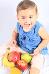 Fototapeta premium Baby mit grünen Augen hat Obst vor sich