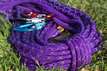Fototapete Bergsteigen Purple climbing rope on green grass  © alexbrylovhk