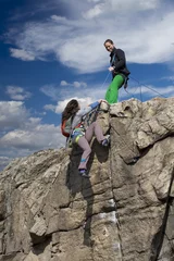Rolgordijnen Climber helps her partner to rich the summit © alexbrylovhk