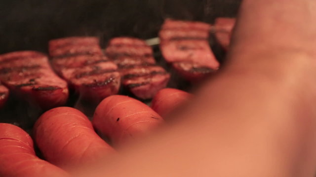 Chef arranges sausages on grill