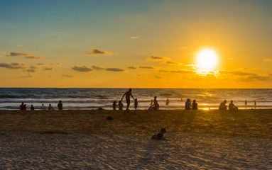 people playing in tropical beach at sunset