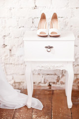 Fototapeta na wymiar Beautiful white wedding shoes on the white vintage bedside table
