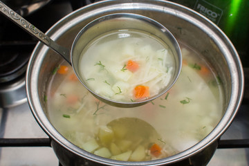 chicken soup with vegetables cooked in a pan. ladle soup


