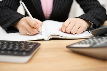 businesswoman writing notes at her desk