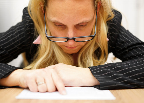 Woman with glasses reading document very precise and pointing to
