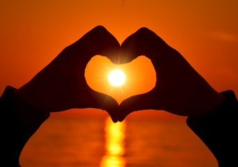 Romantic Heart Shape with hands at sunset