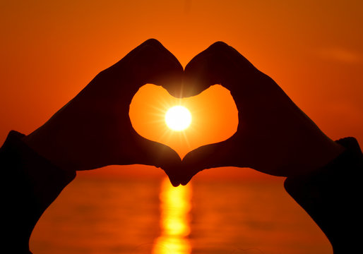 Romantic Heart Shape with hands at sunset