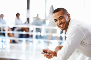 Portrait of man in office with telephone, smiling