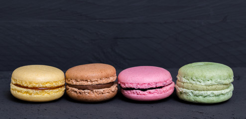 Bunte Macarons auf schwarzem Holz