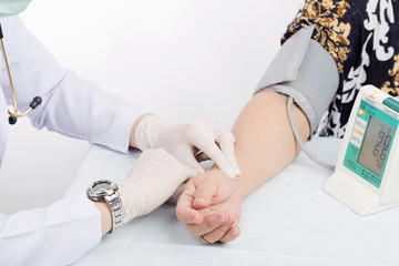 Obraz premium Doctor checking pulse of patient with stethoscope on table isol