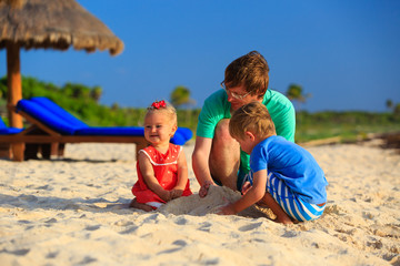 father and two kids playing with sand on the beach