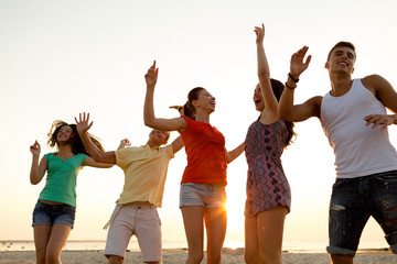 Obraz premium smiling friends dancing on summer beach