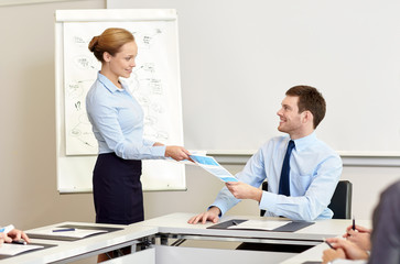 Obraz premium smiling woman giving papers to man in office