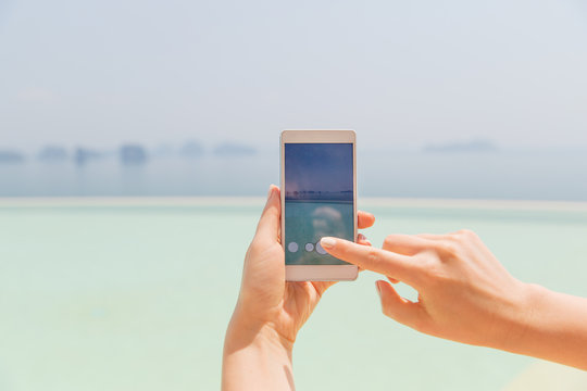 close up of female hand with smartphone on beach