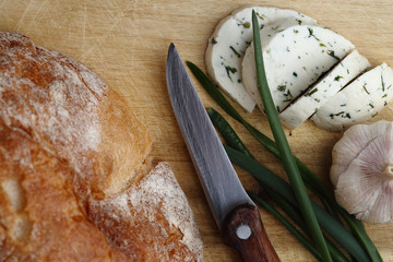 Cheese, green onion, garlic and bread on the wooden board