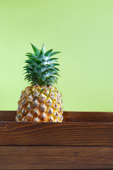 ripe pineapple in a wooden box on a colored background