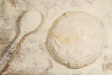 fresh dough for pastry and spoon with flour on wooden background