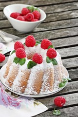 Bundt cake with fresh raspberries on a rustic dark background