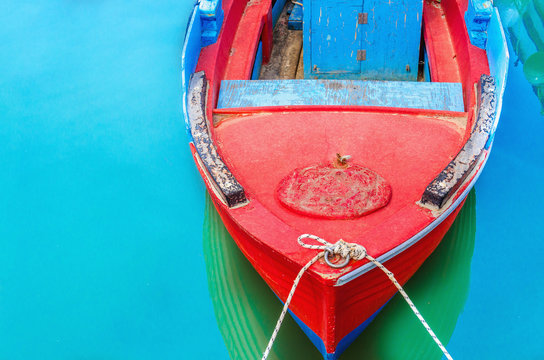  Empty red wooden boat with blue broadside moored in port with s