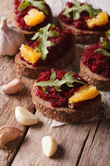 Canape with beets, oranges and arugula close-up. Vertical
