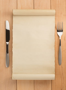 parchment and fork with knife on wood
