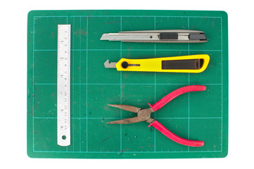 Fototapeta premium Green cutting mats with iron ruler pliers and cuter on white bac