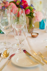 cutlery, wine glasses and flowers on a table at a wedding party