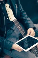 Man with tablet and electric guitar