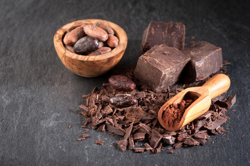 Chocolate, cocoa beans and cocoa powder on a stone background