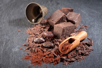 Chocolate, cocoa beans and cocoa powder on a stone background