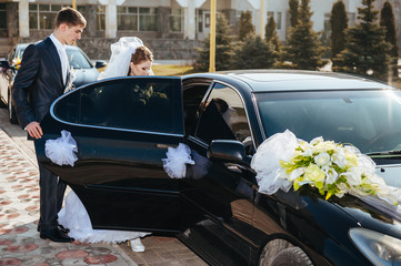 Bride and groom kissing in limousine on wedding-day.