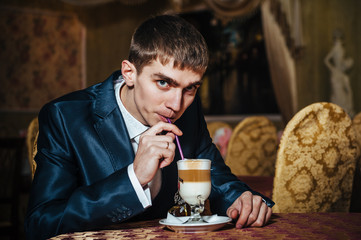 Handsome man drinking coffee at in cafe. Groom's hands holding