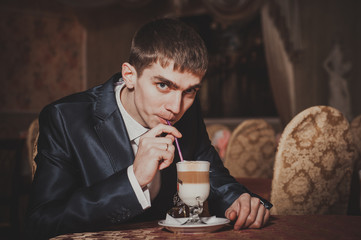 Handsome man drinking coffee at in cafe. Groom's hands holding