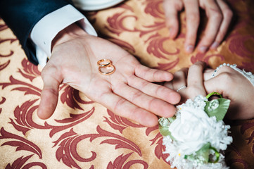 Wedding Couple's hands on the table and rings, bridal bouquet