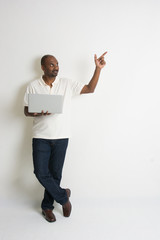 happy casual indian male with a laptop looking at somewhere