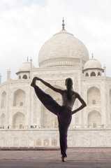 Young female practising yoga pose at Taj Mahal