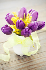 Bouquet of purple tulips and mimosa in vase