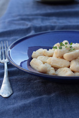 Gnocchi with oregano on a blue plate.