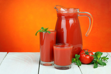 A glass of tomato juice and fresh tomatoes on a wooden table