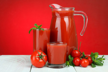 A glass of tomato juice and fresh tomatoes on a wooden table