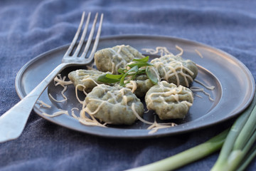 Gnocchi with spinach and grated cheese on a tin plate.