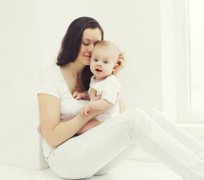 Happy photo young mother with baby at home in white room near wi
