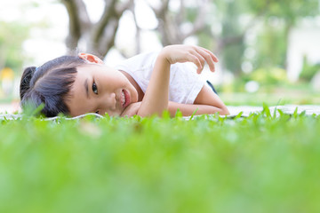 Naklejka na ściany i meble Asian kid portrait with relax pose in the green garden
