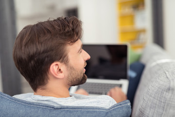 mann mit laptop zuhause auf dem sofa