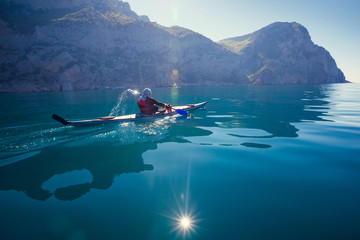 Kayak. People kayaking in sea with calm blue water mountains